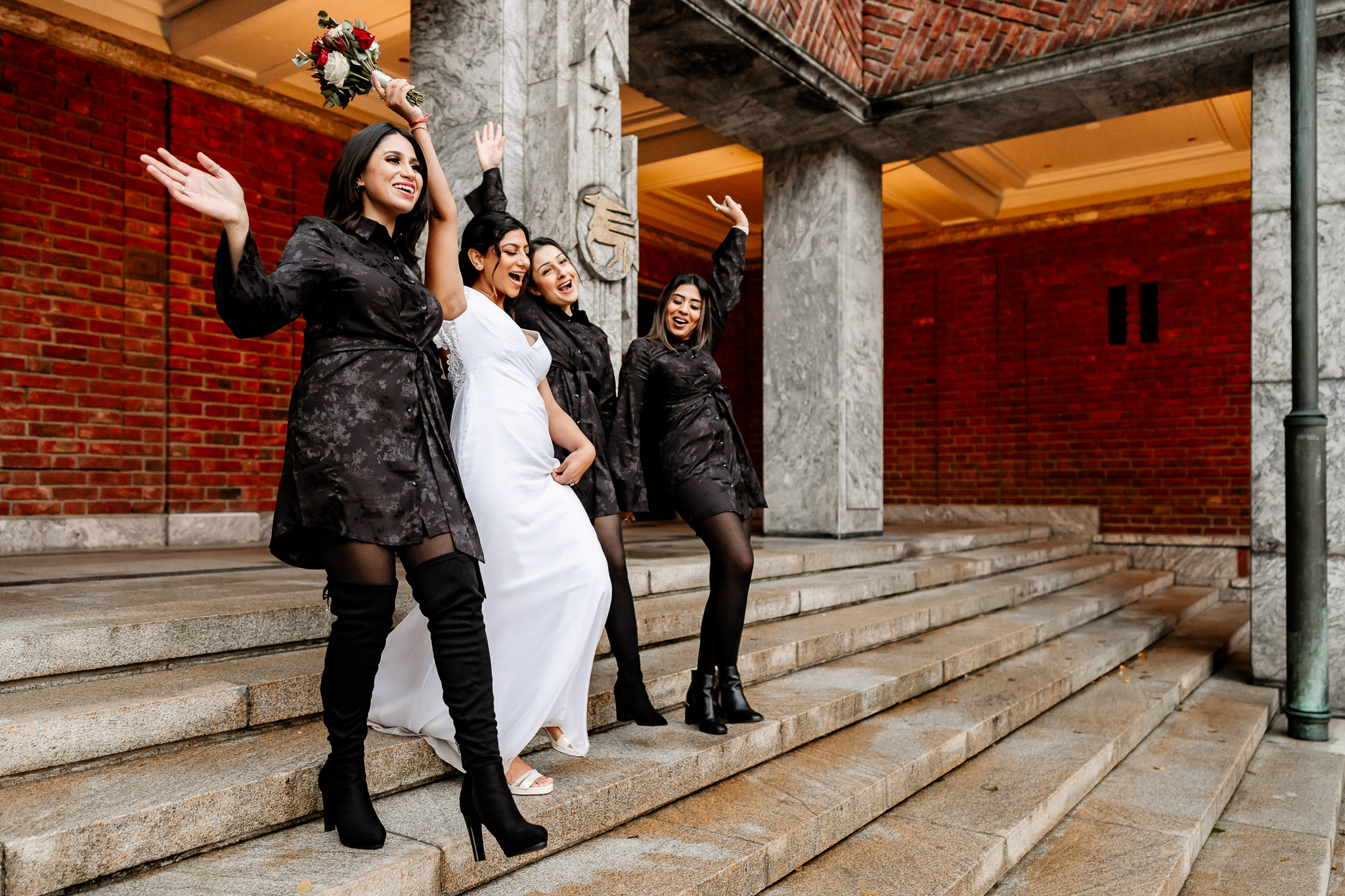 A bride and three bridesmaids walking down the stairs at Oslo City Hall