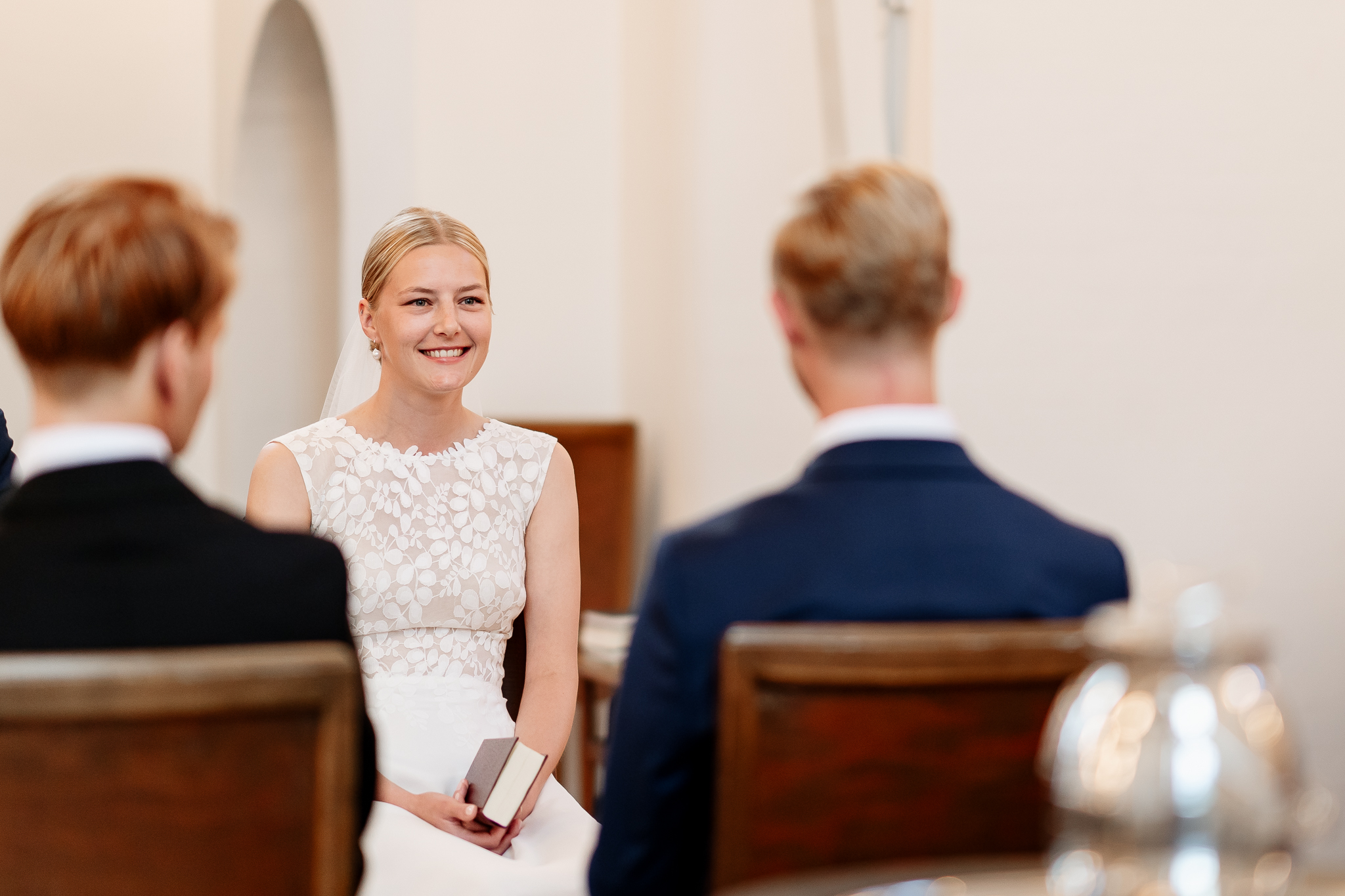 A bride sitting on a chair with a hymn book